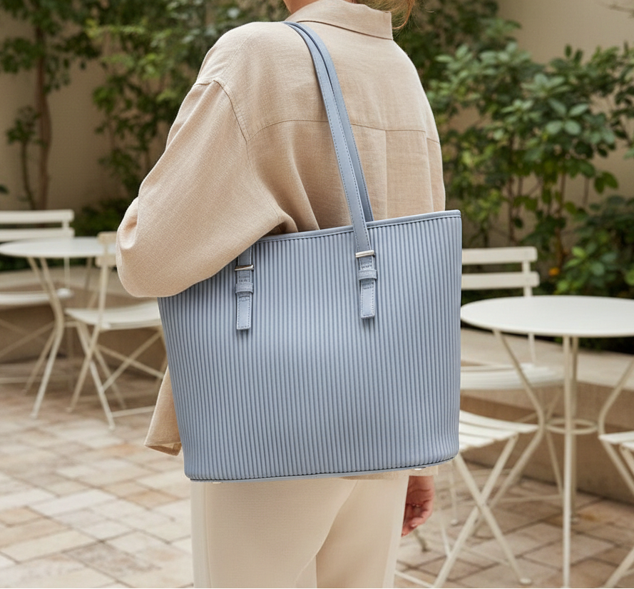 Vuemod Person holding a blue striped tote bag in an outdoor setting with tables and chairs.